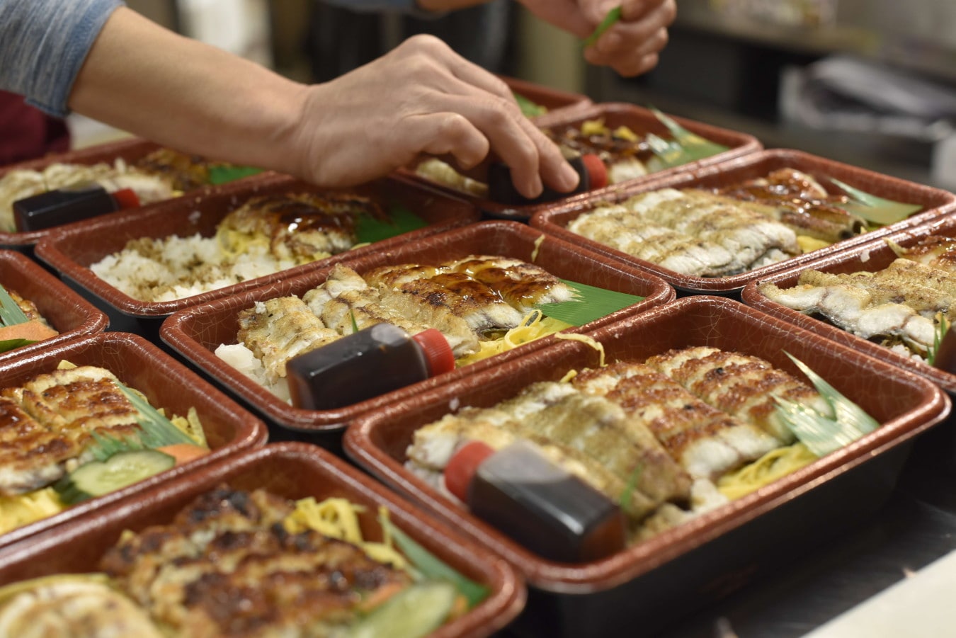 たくさんのうな丼弁当を詰めるようす