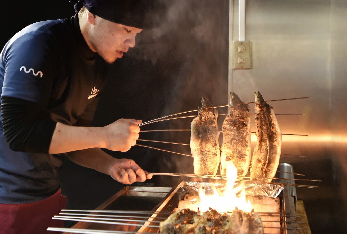 串に刺したうなぎを焼くスタッフ